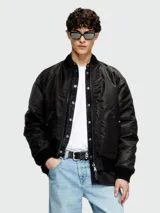 Campera bomber negra con acabado satinado, cierre frontal con cremallera y solapa con botones a presión. Presenta cuello, puños y ruedo de tejido acanalado, y bolsillos laterales con cierre.