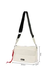 Bandolera negra con correa ajustable, cierre de cremallera en el compartimento principal y bolsillos frontales. Incluye un detalle de cordón rojo y un llavero en espiral negro.