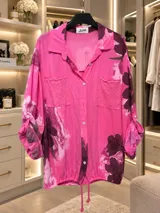 Camisa blanca de manga larga con estampado floral en tonos bordó y verde, cuello camisero, cierre frontal de botones y bolsillos en el pecho con apliques de lentejuelas.