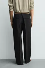 Pantalón de corte wide fit y largo cropped, confeccionado en tejido con elasticidad. Presenta cintura con pliegues frontales, bolsillos laterales y bolsillos traseros de vivo. Cierre frontal con cremallera y botón.