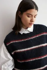 Chaleco de tejido de punto sin mangas, con diseño de rayas horizontales en azul marino, blanco y rojo. Presenta cuello redondo y terminaciones acanaladas.
