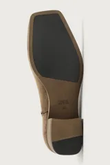 Bota corta de piel con acabado de serraje, diseño de horma cuadrada y tacón bloque de madera. Cuenta con cierre de cremallera lateral.