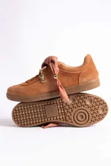Zapatillas de gamuza color marrón con suela de goma color caramelo. Presentan cordones al tono y un detalle decorativo de pañuelo estampado atado en los laterales con esferas metálicas doradas.