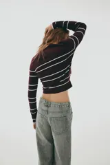Sweater de punto color bordó con rayas horizontales blancas. Tiene cuello redondo y corte corto (crop).