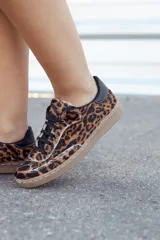 Zapatillas bajas con estampado animal print de leopardo, con cordones negros y suela color caramelo.