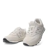 Championes urbanos New Balance modelo 574, color marfil, confeccionados en gamuza y malla con detalles texturizados en la puntera. Presentan el logo N característico en los laterales y suela con diseño moteado.