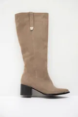 Bota bucanera de cuero color marrón oscuro, con taco cuadrado de 6 cm y punta fina con detalle metálico. Presenta una tira vertical decorativa con tachas metálicas en la parte superior de la caña.