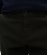 Pantalón slim de sarga lavada color marrón, con cierre de botón y cremallera, trabillas para cinturón y bolsillos laterales y traseros.
