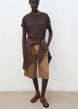Short estilo jort de tiro medio, confeccionado en tejido de algodón. Presenta diseño recto con pinzas frontales, cierre de botón y cremallera, bolsillos laterales y bolsillos de ribete en la parte posterior. Incluye un cinturón ajustable a tono.