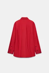 Camisa oversize verde de popelina de algodón, con cuello solapa, manga larga y cierre frontal con botones ocultos bajo solapa.