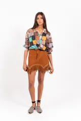 Minifalda de gamuza color marrón, con detalles de tachas doradas y flecos en el ruedo.