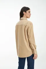 Camisa marrón de pana con cuello clásico, cierre con botones y dos bolsillos frontales con solapa.