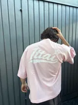 Remera rosa de corte holgado con estampado trasero de la palabra "Ittai" en blanco con una estrella.