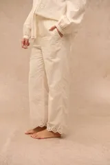 Pantalón Anel de corte recto y holgado, color blanco, confeccionado en tela con diseño bordado o broderie con motivos florales y detalles calados en toda la prenda, incluyendo los bolsillos laterales y el ruedo.