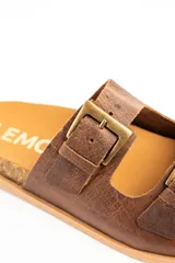 Sandalias de cuero marrón, con dos tiras anchas ajustables mediante hebillas metálicas doradas. Cuenta con una suela de corcho y base dentada.