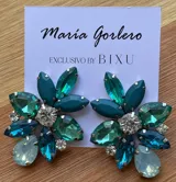Par de caravanas con forma de flor, con pétalos de diferentes tamaños y colores: fucsia, violeta y rojo. En el centro tienen un cristal facetado y pequeños strass blancos.