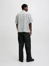 Camisa de manga corta con cuello resort y corte amplio. Presenta un estampado geométrico y botánico en tonos azul y crema. Confeccionada en una mezcla de viscosa y lino, ofrece un acabado liviano y fresco.