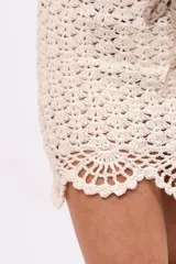 Minifalda color crema tejida a crochet con cintura con cordón ajustable.