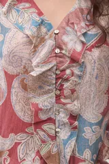 Blusa de manga larga con escote en V y volados en el frente. Presenta un estampado paisley en tonos rojo, azul y beige.