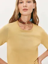 Blusa de punto fino color mostaza con cuello redondo y mangas cortas, de corte ajustado.