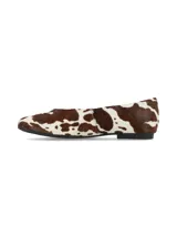 Ballerinas planas confeccionadas en cuero con pelo con estampado animal print de vaca en tonos marrón y blanco, con suela fina y talón cerrado.