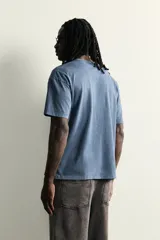 Remera de corte relaxed fit con efecto lavado, cuello redondo y manga corta. Presenta un estampado frontal de texto en tono contrastante.