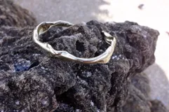 Brazalete rígido abierto de bronce con textura irregular.