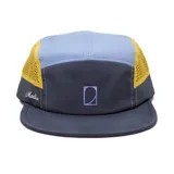 Gorra tipo 7 paneles con diseño deportivo, combinando paneles en gris oscuro, celeste y detalles laterales en amarillo con tejido de malla transpirable. Presenta un logo bordado en el panel frontal y el nombre de la marca bordado en el lateral.
