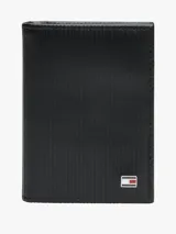 Billetera plegable Tommy Hilfiger confeccionada en piel negra con textura acanalada. Presenta un logo esmaltado distintivo de la marca en la parte frontal.