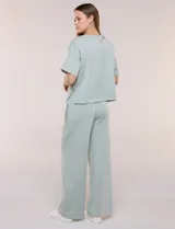 Conjunto de buzo de manga corta con hombros caídos y escote redondo, acompañado de un pantalón tipo wide leg de tiro alto con cintura elástica y cordón de ajuste, en color verde.