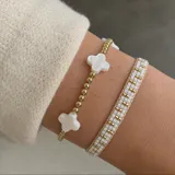 Pulsera tejida a mano con cuentas Miyuki blancas y doradas, con diseño regulable.