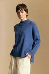 Polera de tejido de punto color blanco, con cuello alto acanalado, hombros caídos y detalle de costura vertical en el frente.