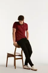 Pantalón de jean negro de corte slim fit, con diseño clásico de cinco bolsillos, presillas para cinturón y cierre frontal con botón y cremallera.