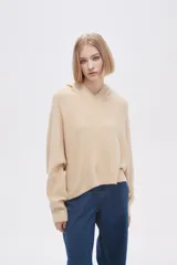Sweater color beige de tejido de punto con capucha y corte irregular.
