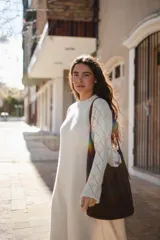 Vestido largo de punto color crudo, con cuello redondo, mangas largas acampanadas y diseño calado en las mangas y en el ruedo. Presenta una costura central vertical en el frente.