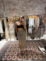 Pollera midi de satén color beige, con diseño de frunces laterales y tajo frontal.