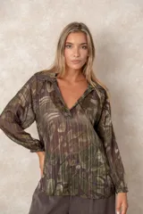 Blusa de gasa con estampado abstracto en tonos verdes y marrones, con detalles de hilos dorados. Presenta cuello camisero con escote en V, mangas largas con puños elásticos y un corte holgado.