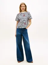 Remera Tommy Hilfiger de corte regular, confeccionada en punto interlock de algodón blanco con rayas horizontales azul marino y diseño floral gráfico superpuesto con detalles en rojo. Presenta cuello redondo y mangas cortas.