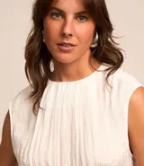 Blusa sin mangas de tejido satinado color blanco, con escote redondo y textura plisada vertical.