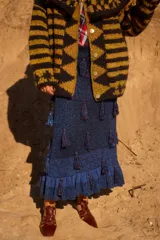 Pollera midi de tejido de punto con lúrex, color azul brillante. Presenta un diseño ajustado con elástico en la cintura, decorada con borlas distribuidas por toda la superficie y terminación con volados en el ruedo.