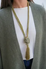 Collar largo de estilo artesanal con cordones de hilo color verde oliva, que presenta un dije central esférico compuesto por hilos metálicos entrelazados y una borla colgante del mismo tono.