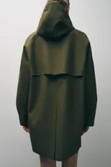 Cazadora impermeable de acabado engomado en color amarillo, con capucha ajustable, cierre frontal con botones a presión, bolsillos laterales y mangas largas ajustables.