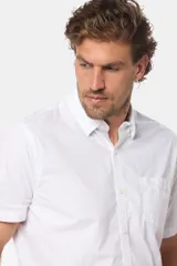 Camisa lisa de manga corta color crema, confeccionada en 100% algodón, con cuello abotonado y un bolsillo en el pecho.