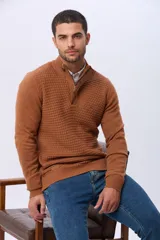 Buzo de punto color beige, con cuello alto y cierre frontal con cremallera y solapa de gamuza con botón. Presenta un tejido texturizado en el cuerpo y mangas lisas.