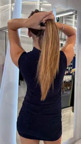 Vestido corto ajustado de cuello alto y sin mangas, confeccionado en tela con acabado brillante y efecto drapeado en los laterales.