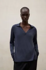 Sweater de punto color azul, con cuello polo y escote en V, de manga larga, corte relajado y largo a la cadera con aberturas laterales.