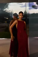 Vestido largo bordó con brillos, escote halter y diseño fluido de corte acampanado.