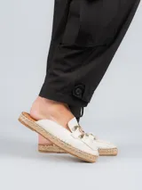 Alpargatas tipo mule color blanco, confeccionadas en cuero, con detalle de herraje metálico dorado en el empeine y suela de yute trenzado.
