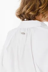 Camisa de corte holgado color marrón chocolate, con cuello clásico, cierre frontal de botones y mangas largas abullonadas con frunces en los hombros.