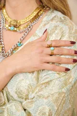 Anillo dorado con diseño trenzado y turquesa sintética engarzada.